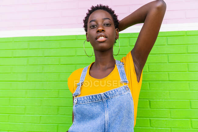 Молодая афроамериканка стоит на красочной яркой стене — стоковое фото