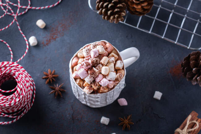 Desde arriba de taza de cerámica con cacao dulce con malvaviscos cerca de conos de abeto y cuerda para atar regalos de Navidad - foto de stock