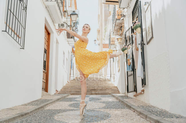 Повне тіло розкішної жінки в взутті, що виконує витончений балетний рух з піднятою ногою і рукою — стокове фото