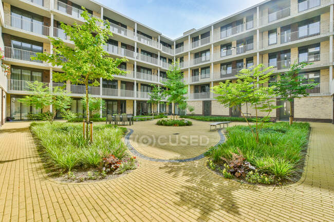 Passarela de tijolo que vai entre árvores verdes e plantas no quintal interno do edifício condomínio moderno — Fotografia de Stock
