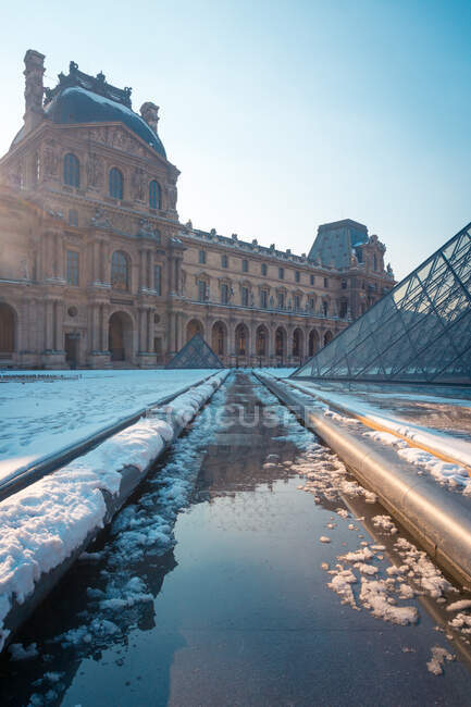 Old stone building facade against water channel between pavements with snow on sunny day in Paris France — Stock Photo