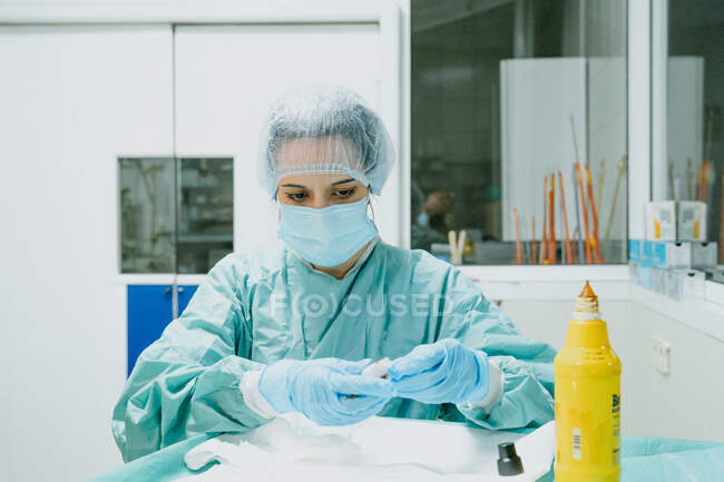Focused female vet in surgical uniform applying iodine on cotton wool at table in clinic — Stock Photo