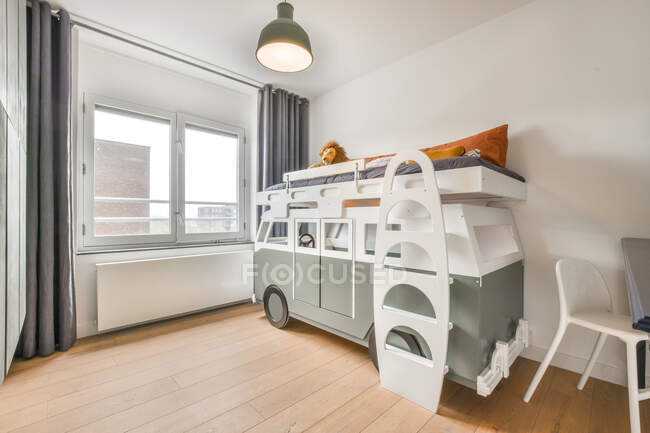 Interior de espaçosas crianças quarto com cama em forma de carro e paredes brancas em apartamento moderno durante o dia — Fotografia de Stock