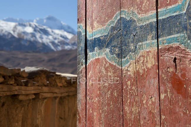 Alte Holzwand mit Kratzern und rissiger Farbe von Gebäuden, die von hohen schneebedeckten Berggipfeln in Nepal umgeben sind — Stockfoto