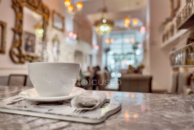 Taza de cerámica de café aromático en la mesa con servilletas en la cafetería - foto de stock