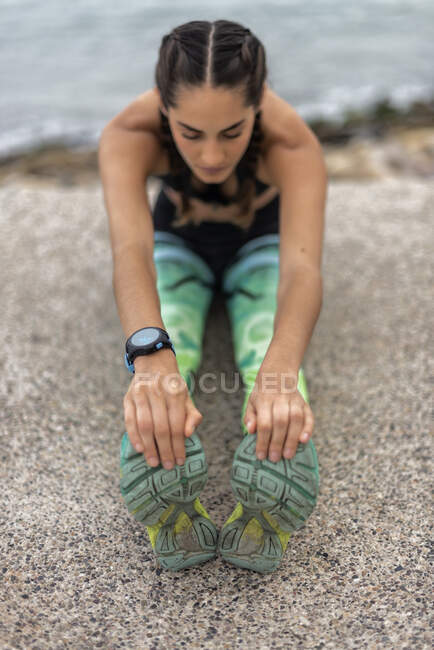 Ritaglia irriconoscibile corridore femminile allungamento delle gambe e facendo esercizio lunge in avanti durante l'allenamento sul lungomare in estate — Foto stock