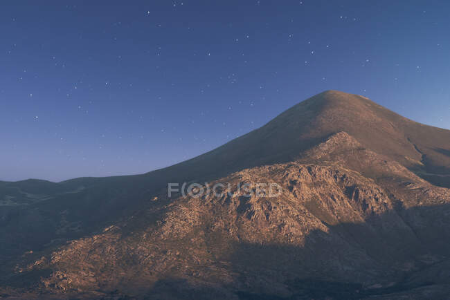 Picturesque landscape of mountain range under starry sky illuminated by sun at sunrise — Stock Photo