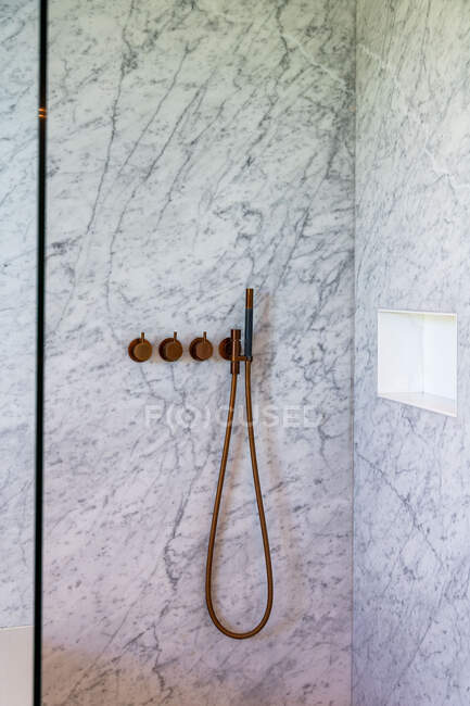 Душевая кабина с современным краном и мраморной плиткой стен в минималистской светлой ванной комнате — стоковое фото