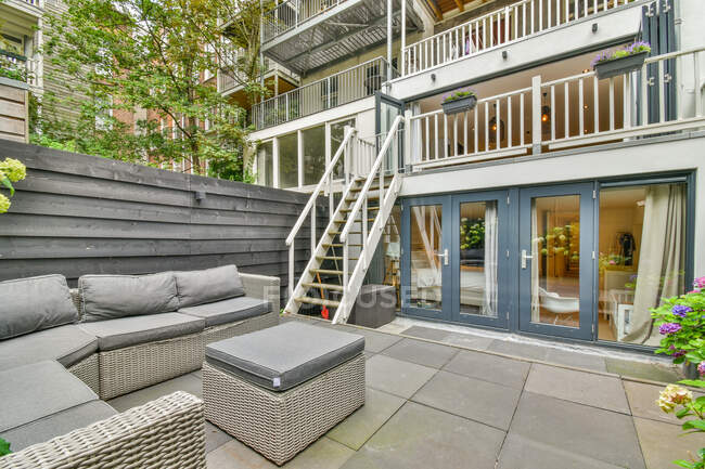 Patio avec table et canapé contre bâtiment contemporain avec escalier et balcon clôturé en ville — Photo de stock