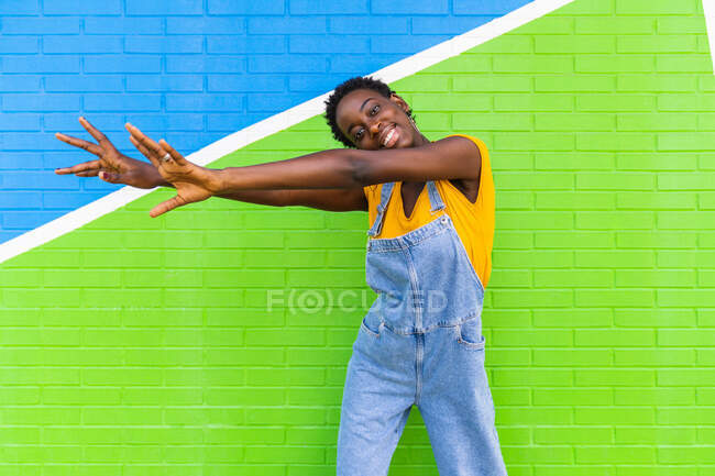 Happy young African American female smiling while standing on colorful bright wall — Stock Photo