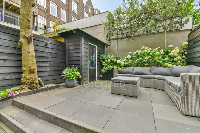 Backyard with staircase against sofa between table and blooming flowers in daytime — Stock Photo