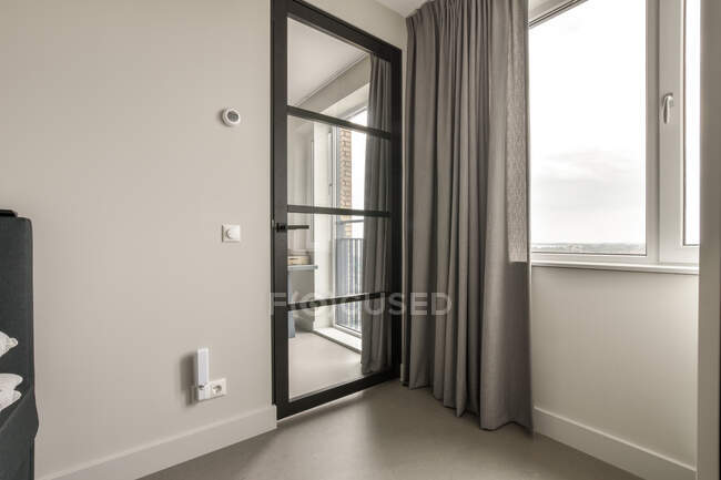 Glastür neben Fenster mit grauen Vorhängen im hellen Raum in der Wohnung tagsüber — Stockfoto