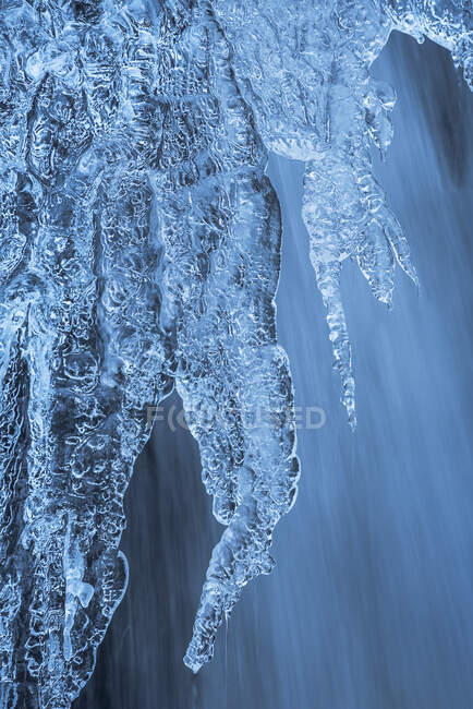Texture di ghiaccio freddo irregolare chiaro sopra il flusso d'acqua che scorre nella natura invernale — Foto stock