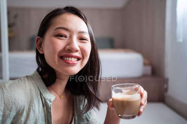 Side view of delighted young ethnic female blogger at desk with netbook at home — Stock Photo