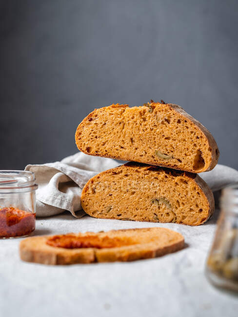 Scheibe Brot mit appetitanregender roter Pesto-Sauce auf Tisch vor grauem Hintergrund serviert — Stockfoto
