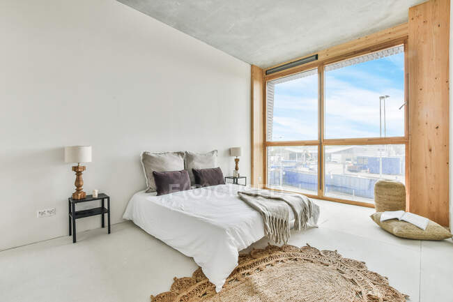 Conception créative de chambre avec coussins et couverture sur le lit sur le sol à la maison à côté de la fenêtre — Photo de stock