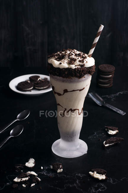 Зверху смачний молочний коктейль з подрібненим печивом і соломою в склянці з шоколадним соусом — стокове фото