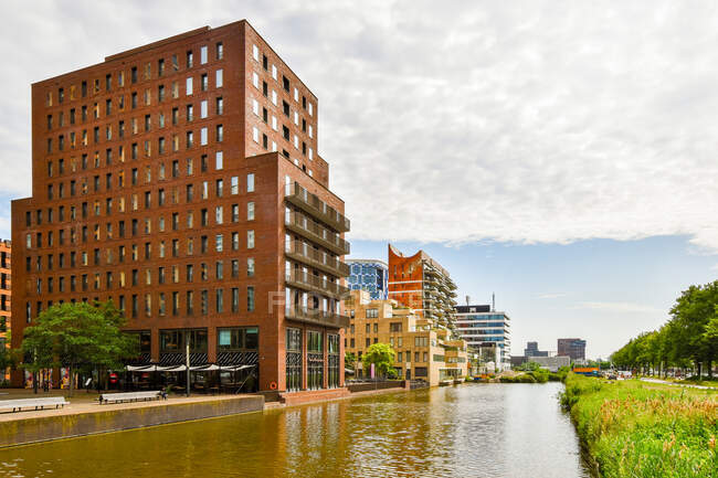 Fiume increspato tra parco e contemporanea casa residenziale esterni sotto cielo nuvoloso ad Amsterdam Olanda — Foto stock