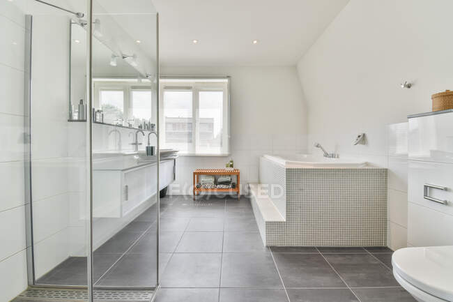 Сучасний інтер'єр ванної кімнати з душовою кімнатою проти ванни і вікна в будинку з плиткою підлоги — стокове фото