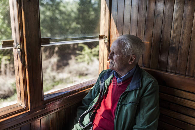 Uomo attraente e vecchio che viaggiano in una vecchia carrozza di legno che guarda fuori dalla finestra — Foto stock