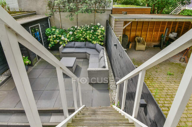 From above of backyard with staircase against sofa between table and blooming flowers in daytime — Stock Photo