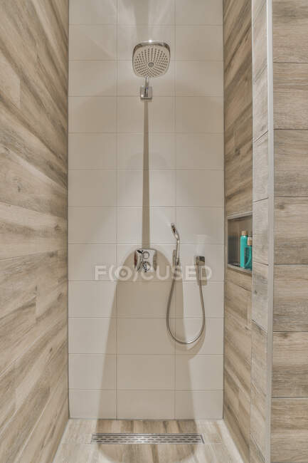 Chuveiro e produtos de higiene pessoal em casa de banho com paredes de azulejos em casa residencial moderna — Fotografia de Stock