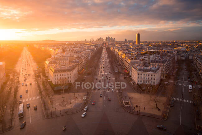 Vue par drone des façades des maisons urbaines et des routes avec transport sous un ciel nuageux brillant au coucher du soleil à Paris France — Photo de stock