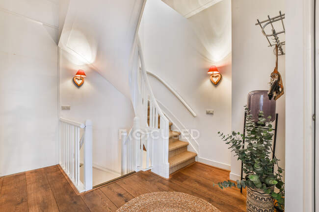 Інтер'єр просторого залу з дерев'яною підлогою і вигнутими творчими сходами в сучасному котеджі — стокове фото
