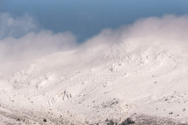 Grave pendio di montagna coperto di neve e nuvole nella fredda giornata invernale nel Parco Nazionale della Sierra de Guadarrama — Foto stock