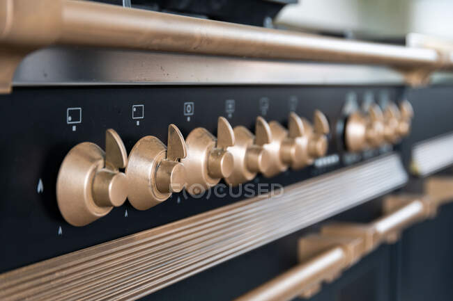 Botões de controle de aço inoxidável de bronze no painel frontal do fogão moderno na cozinha leve — Fotografia de Stock