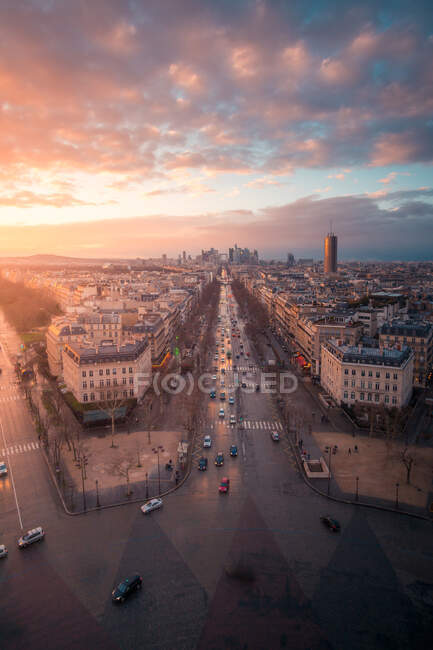 Drone view of urban house facades and roadways with transport under shiny cloudy sky at sundown in Paris France — Stock Photo