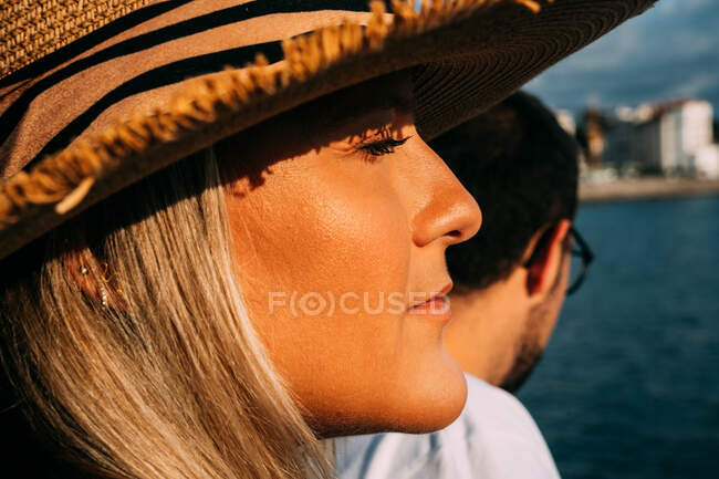 Vista lateral de la cosecha turista femenina contra novio barbudo en gafas de vista contemplando el océano mientras mira hacia otro lado en Saint Jean de Luz Francia - foto de stock