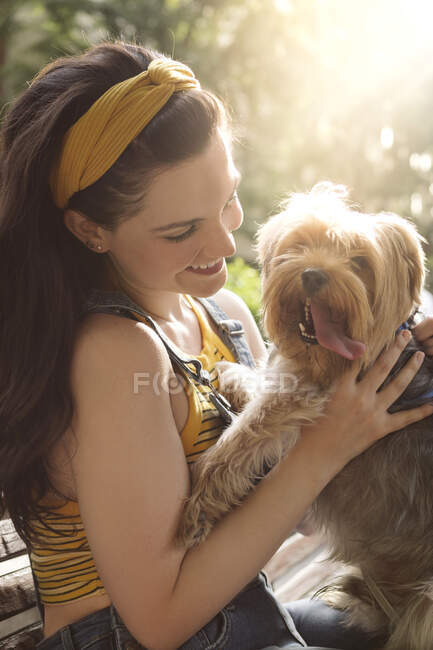 Side view of happy female owner smiling widely while enjoying time with funny Yorkshire Terrier with tongue out — Stock Photo