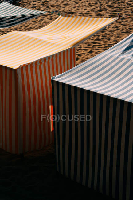 Pavilions with striped ornament and canopies on sandy shore on sunny day in Saint Jean de Luz France — Stock Photo