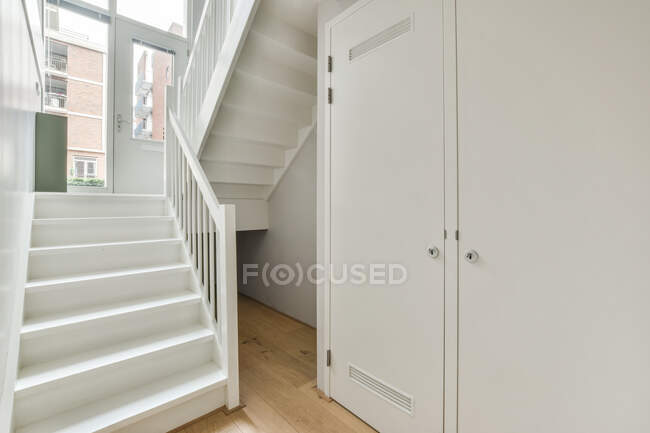 Interno della casa con armadio bianco e scala in legno che conduce al secondo piano — Foto stock