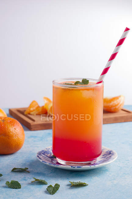 Verre de cocktail Sunrise rafraîchissant avec paille servi sur table avec des oranges fraîches — Photo de stock