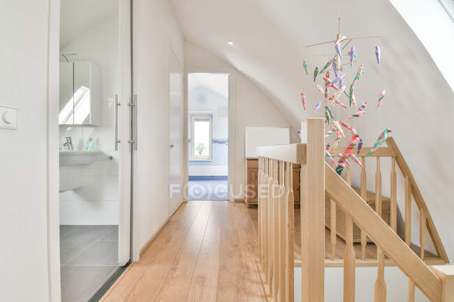 Passaggio interno tra porta di vetro del bagno e origami uccelli appesi a parete a casa alla luce del giorno — Foto stock