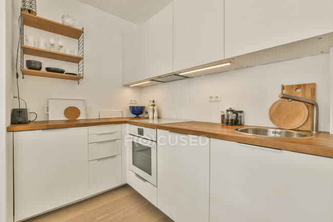 Innenraum der Küche mit weißen Möbeln und Holztheke und Elementen in der modernen Wohnung — Stockfoto