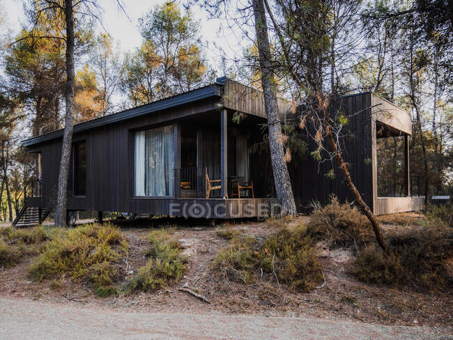 Cottage contemporaneo con esterno in legno e spaziosa terrazza situata nel bosco la sera d'estate — Foto stock