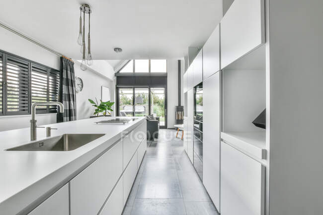 Leichtes Interieur der Küche mit Metallspüle und eingebauten Geräten im modernen Haus — Stockfoto