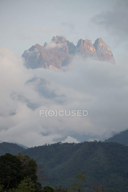 Cenário pitoresco de montanhas rochosas com altas encostas íngremes cobertas com densas neblinas e colinas cobertas de bosques — Fotografia de Stock