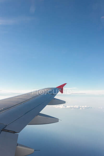 Através da janela da aeronave vista de nuvens fofas acima do mar e do terreno durante a viagem durante o dia — Fotografia de Stock