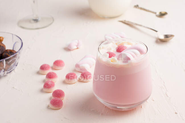 Стакан сладкого горячего белого шоколада с розовыми желе конфеты и зефир подается на белый стол — стоковое фото