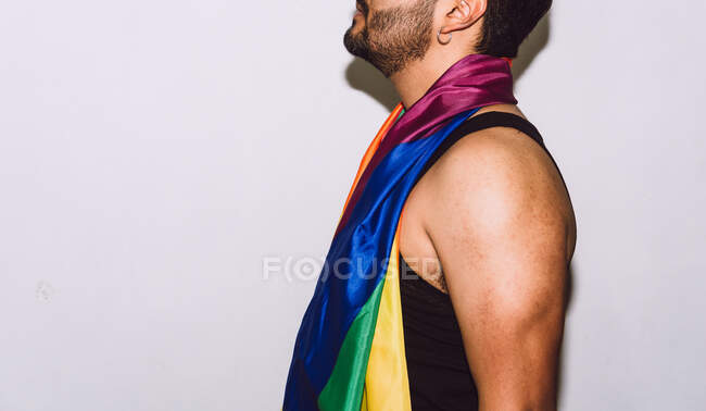 Crop unrecognizable bearded male playing and waving multicolored flag symbol of LGBTQ pride — Stock Photo