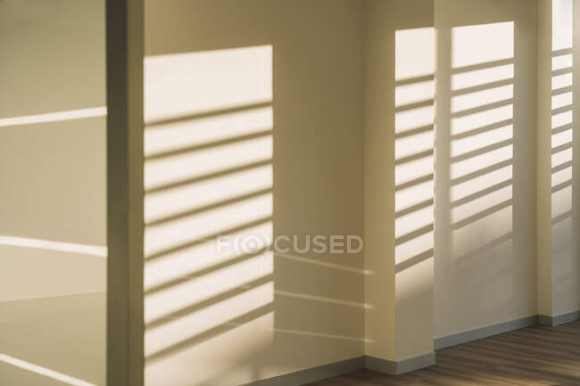 Interior of empty spacious loft hallway with geometrical shadows and sunlight on white walls — Stock Photo