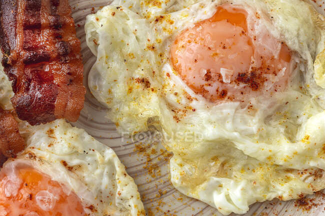 Gustose uova soleggiate con strisce di pancetta fritte sul piatto — Foto stock