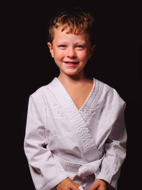Carino ragazzo in karate kimono ridere felicemente con bocca aperto in studio contro nero sfondo — Foto stock