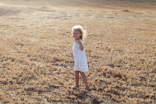 Kleines blondes Mädchen allein auf einem Feld an einem sonnigen Tag — Stockfoto