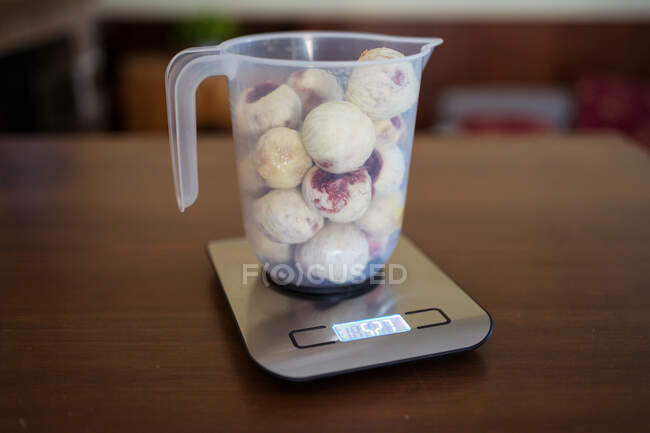 Ripe figs in pitcher on weighing scales with display on table in kitchen — Stock Photo