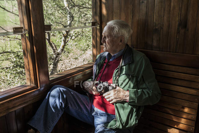 Man taking photos with his old camera through the window of an old wooden train car — Stock Photo